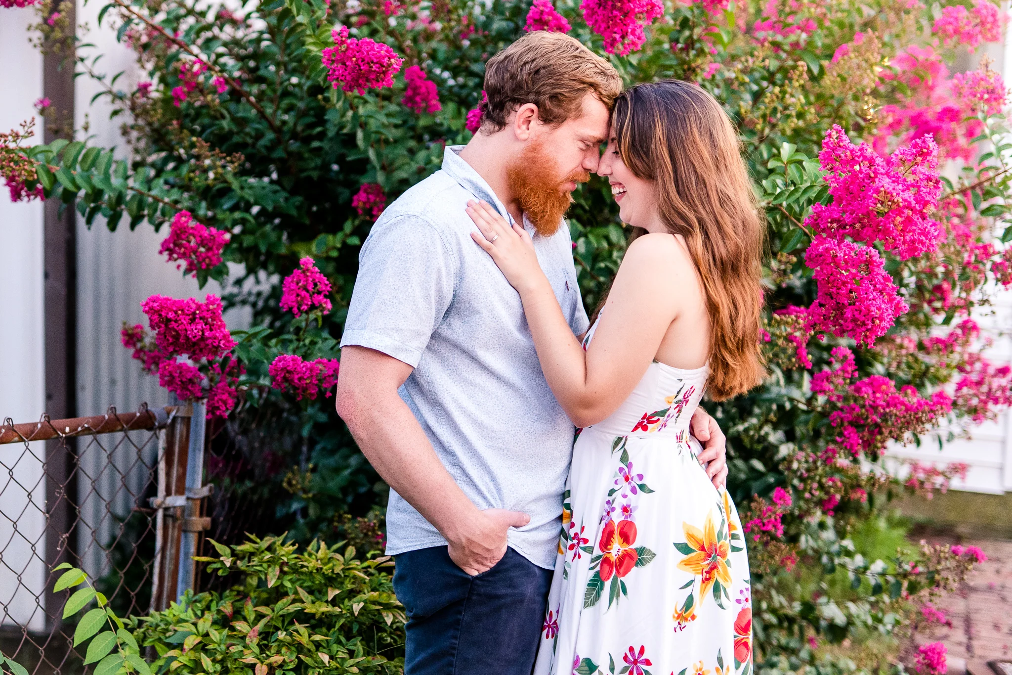 An engaged couple press their foreheads together and laugh during their summer sunset engagement session in Historic Occoquan, Northern Virginia