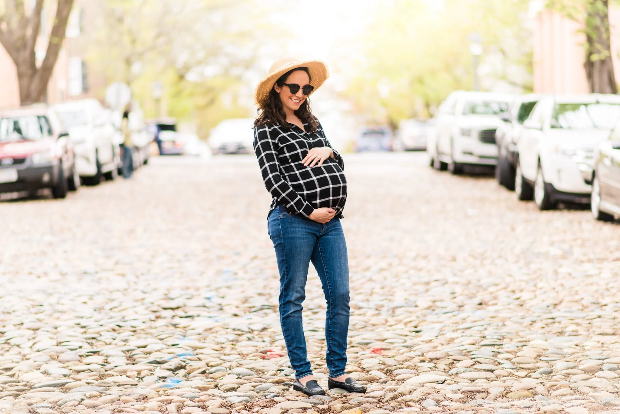 A pregnant woman poses along the cobblestone street during her maternity session in Old Town Alexandria