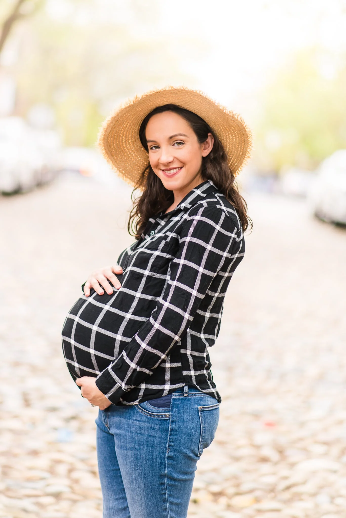 A pregnant woman poses along the cobblestone street during her maternity session in Old Town Alexandria