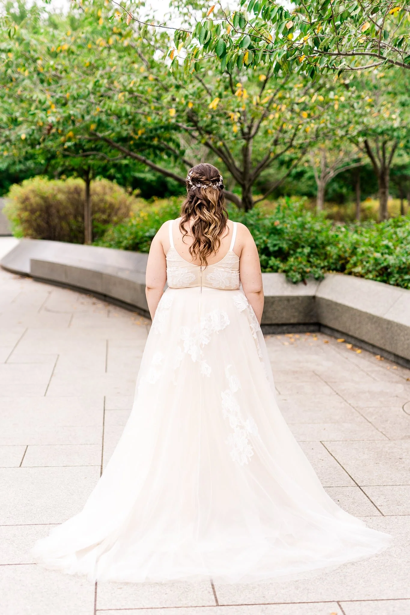 A bride faces away from the camera to show off the details on the back of her dress and her hair on her wedding day at the Tidal Basin near the MLK Memorial in Washington, DC