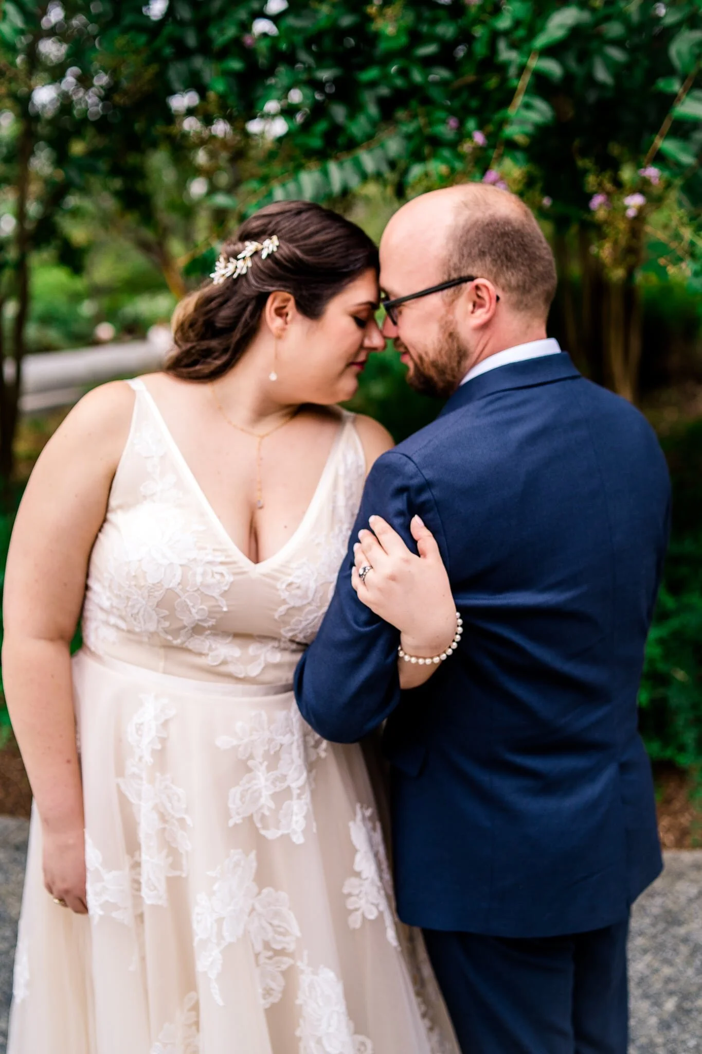 A bride and groom stand together arm in arm with foreheads together on their wedding day at the Tidal Basin by the MLK Memorial in Washington, DC