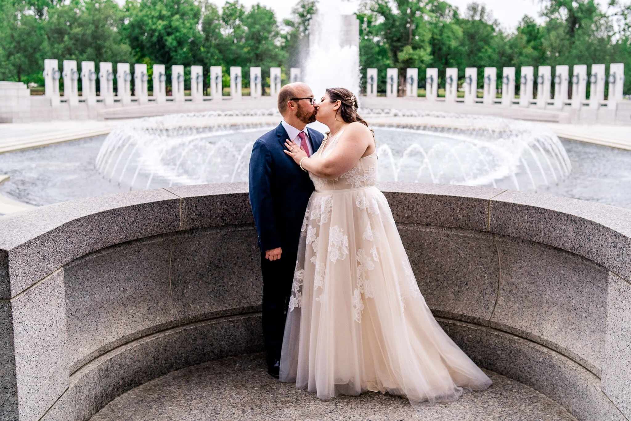 A bride and groom share a kiss on their fall wedding day at the WWII Memorial in Washington, DC