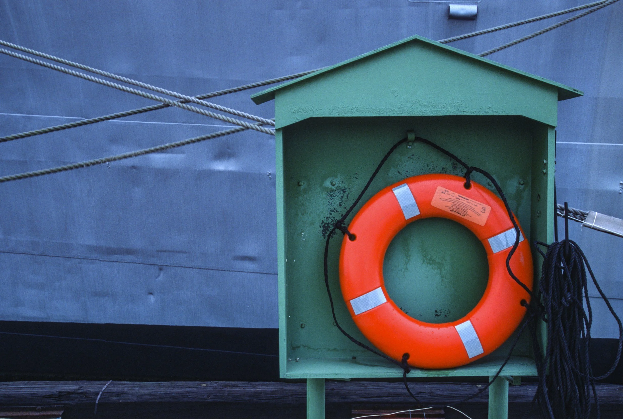 A red and white life preserver in a green hut with a blue background.