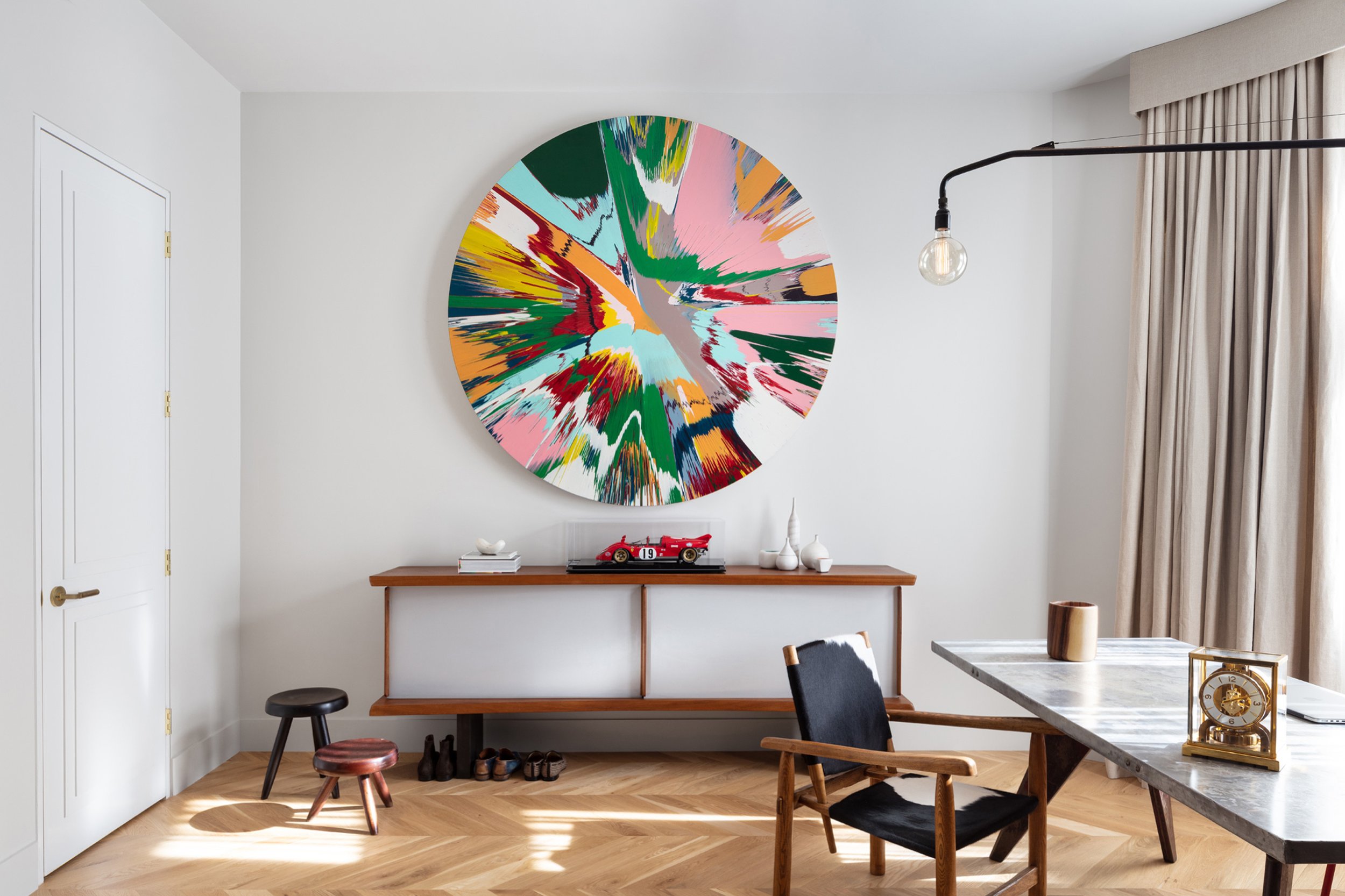  Charlap Hyman &amp; Herrero  Tina Kim Townhouse    A   Damien Hirst “Spin” painting hangs above a Charlotte Perriand cabinet in Tina Kim’s townhouse. The armchair and stools also designed by Perriand, pairs well with the aluminum-top table and arm l