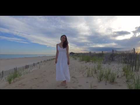 Young brunette woman walking along sand dunes towards camera