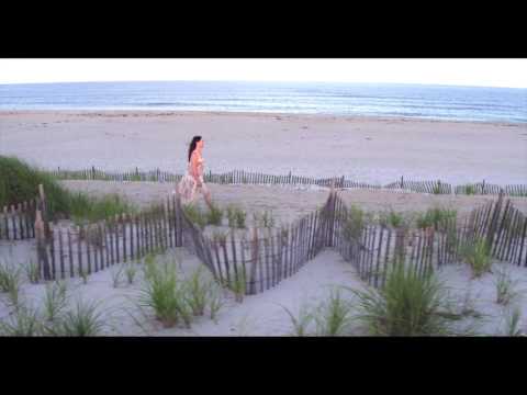Tracking shot of young woman walking along ocean dunes
