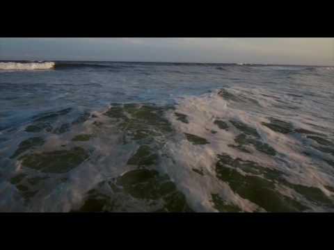 Lower aerial pass over large ocean waves.