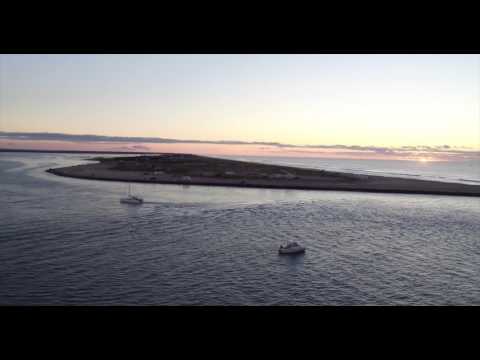 Aerial tracking shot of inlet from ocean to bay at sunrise