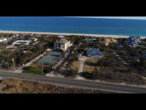 Low aerial flight along lavish oceanfront estates and cottages viewed from Dune Road, Quogue, NY