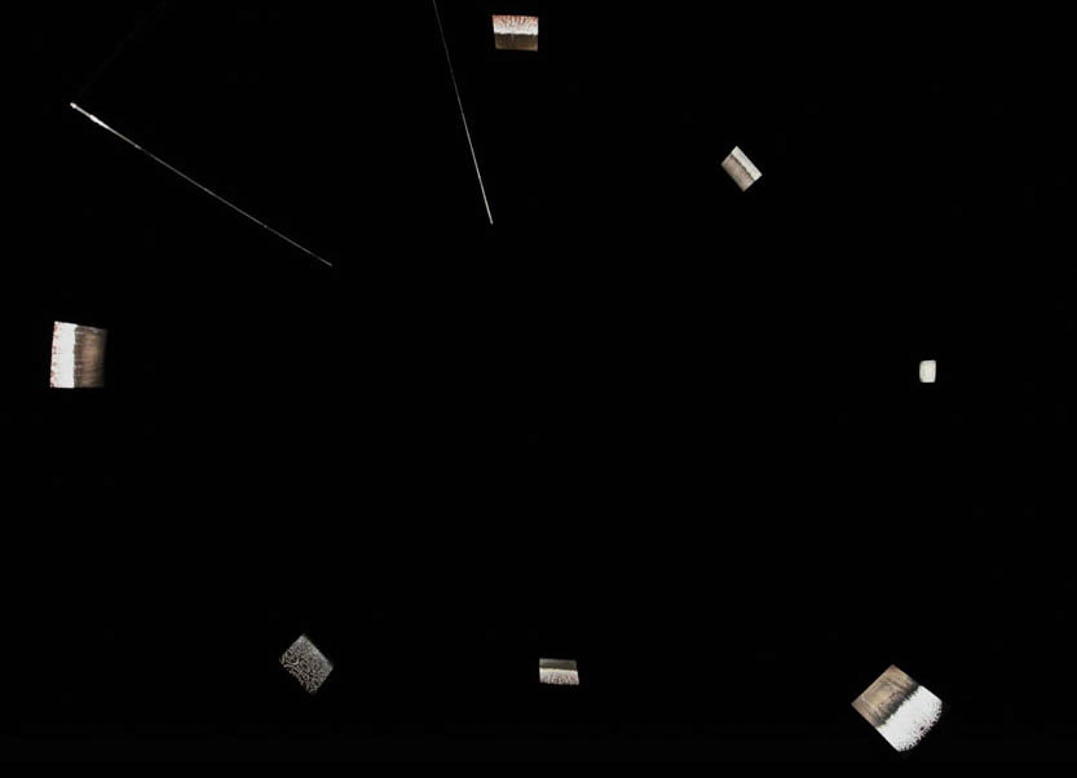The entrance into US affords another suite of reflections in concert with each other. We become enveloped within the darkness of an octogonal theater in reverse. The space is illuminated only by a rise and fall of light emitted from seven screens. Inside the octogon one must physically move from screen to screen to see the moving images from different points of view within 360 degree space. Reflections now fall into the background, shifting focus to the experience of the other — separate but together.