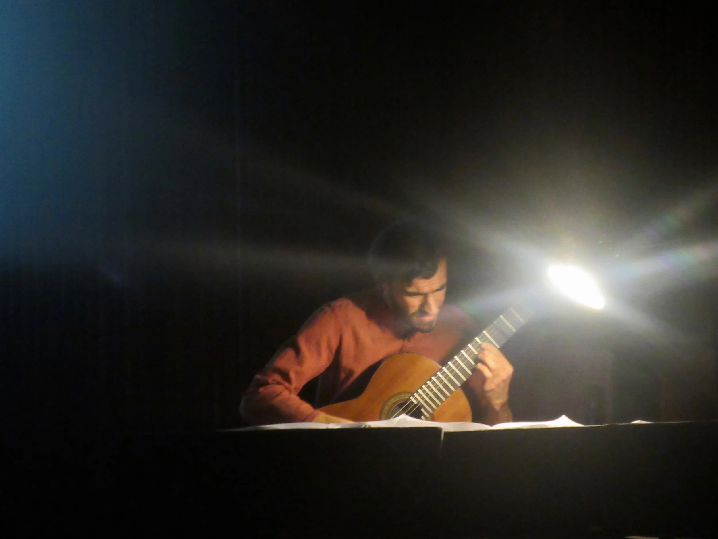 Now set up off to the side and lit by lamplight, with the screen down and showing video, Mohit plays music of Andrew York.