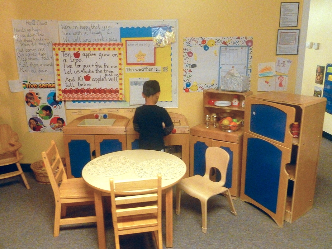 Children build social skills and engage in imaginative play in the kitchen.
