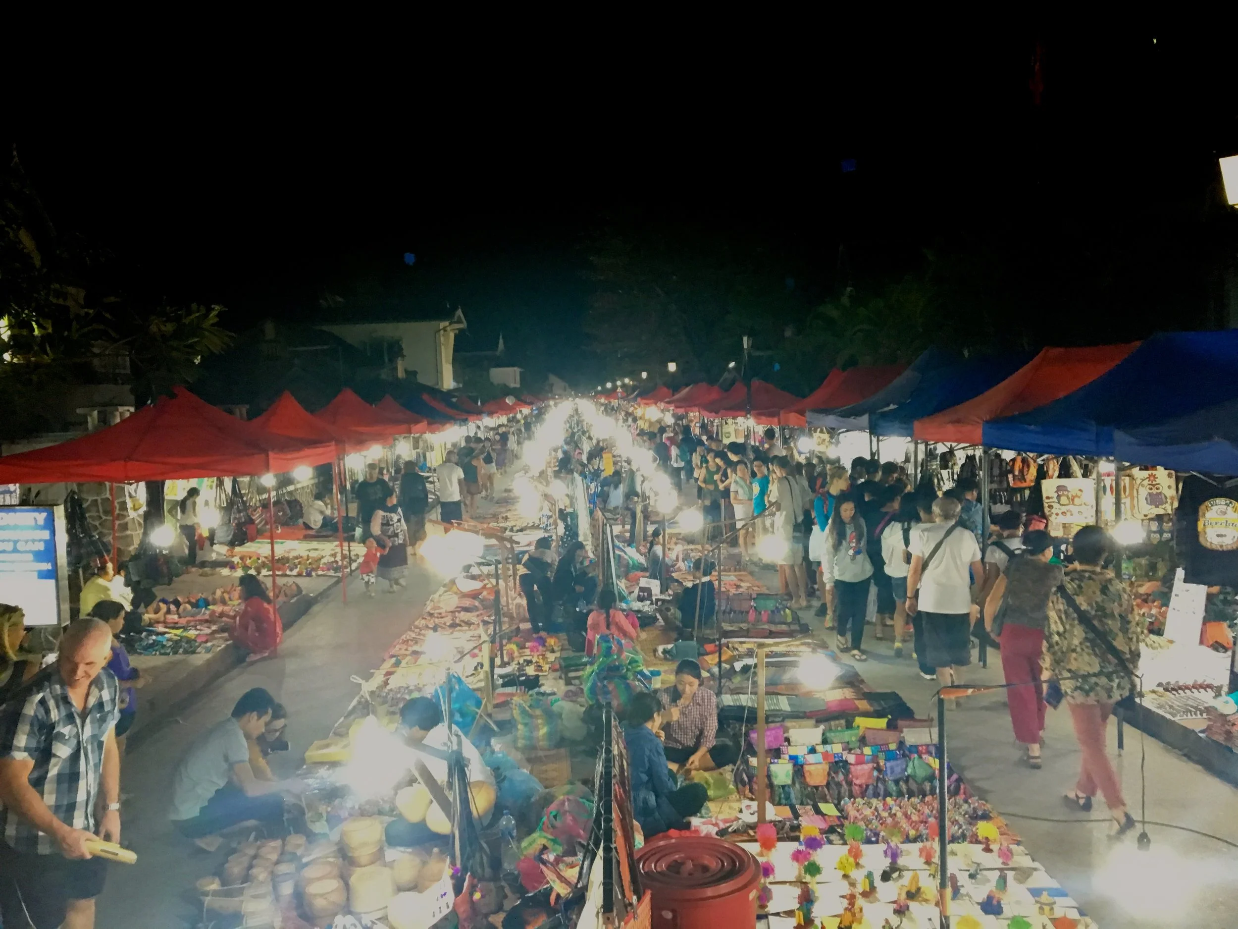 The colorful and vibrant nightly street market scene in Luang Prabang, Laos. The sights, sounds, and smells from this lively night market are enough to entertain anyone. If you want it, they have it here in this 1km long market. Some of our favorite snacks here are the vegetable noodle soup and freshly sliced mango and pineapple. 