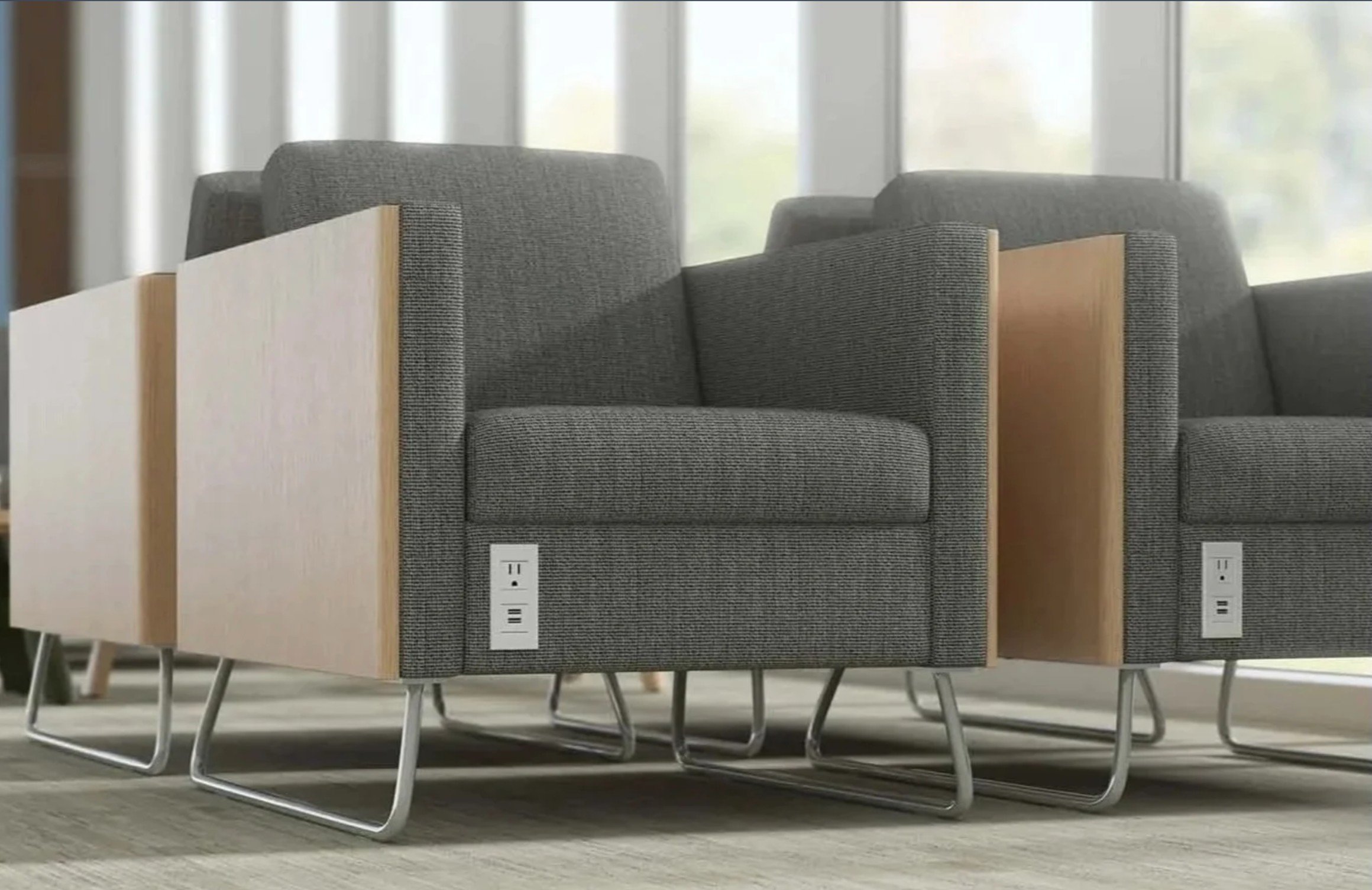 Modern executive lounge seating with integrated power outlets and USB charging ports, gray upholstered chairs, wood panels, and contemporary metal sled bases.