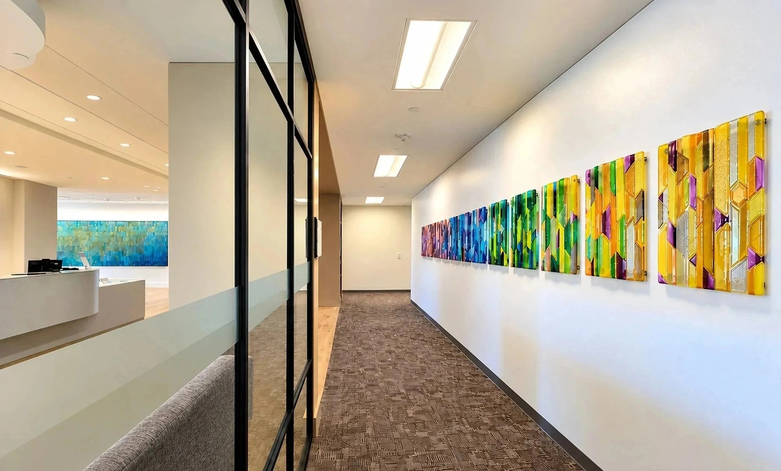 Custom multicolored fused-glass art installation in a contemporary healthcare corridor, curated by Silver Chase Design and recognized as a Top 100 finalist in the 2025 CODAworx CODAawards.