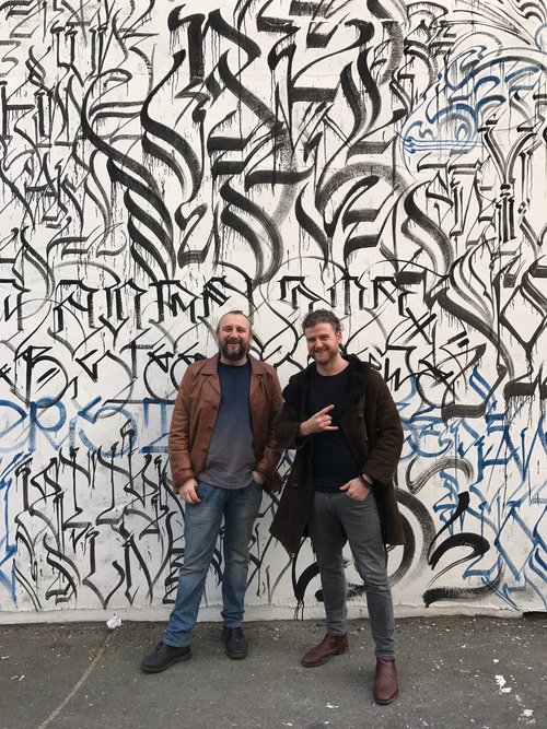 Craig and Jeff in front of artwork by Defer.