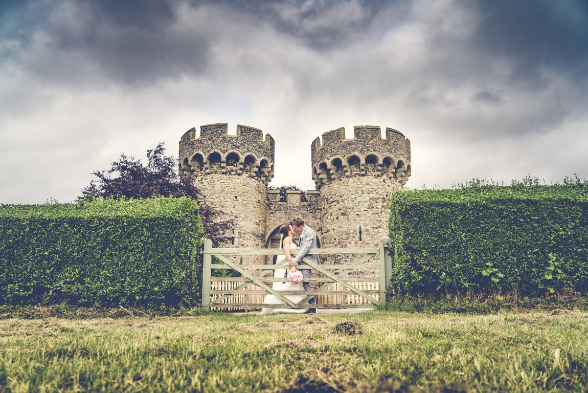 Bride and Groom by fence and castle turrets