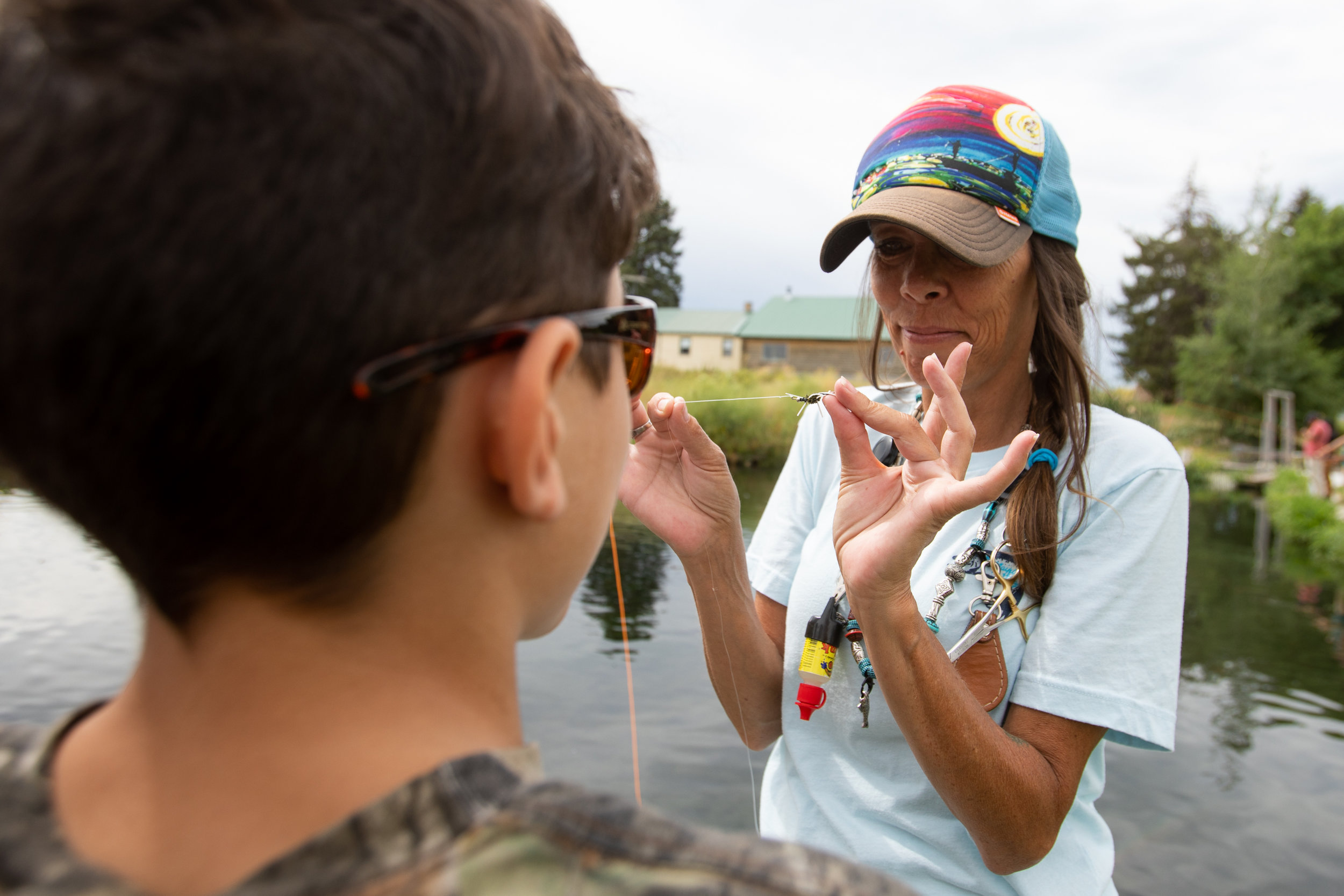  Verlicia Perez, lead mentor for The Utah Mayfly Project, teaches a foster care child how to tie a fly on his fly line at a trout pond on Saturday, July 14, 2018, in Smithfield. The Mayfly Project is a national non-profit that uses fly fishing to men