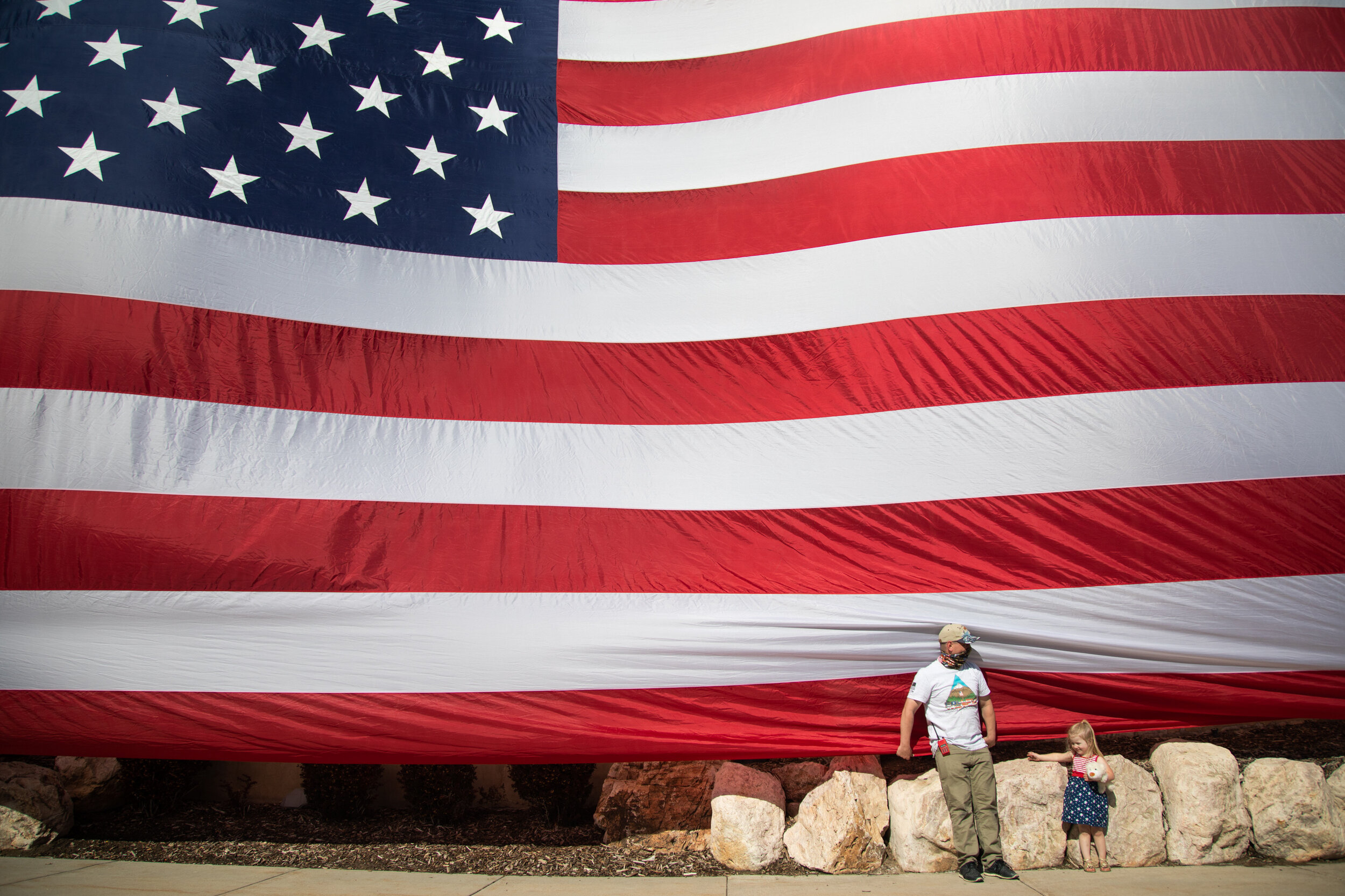  Mark Miller and his daughter Emmalee Miller, 3, stand at the bottom of "The Lieutenant,"  a large American Flag that was unfurled to honor healthcare workers on the frontline dealing with the coronavirus pandemic on Tuesday, April 28, 2020, outside 