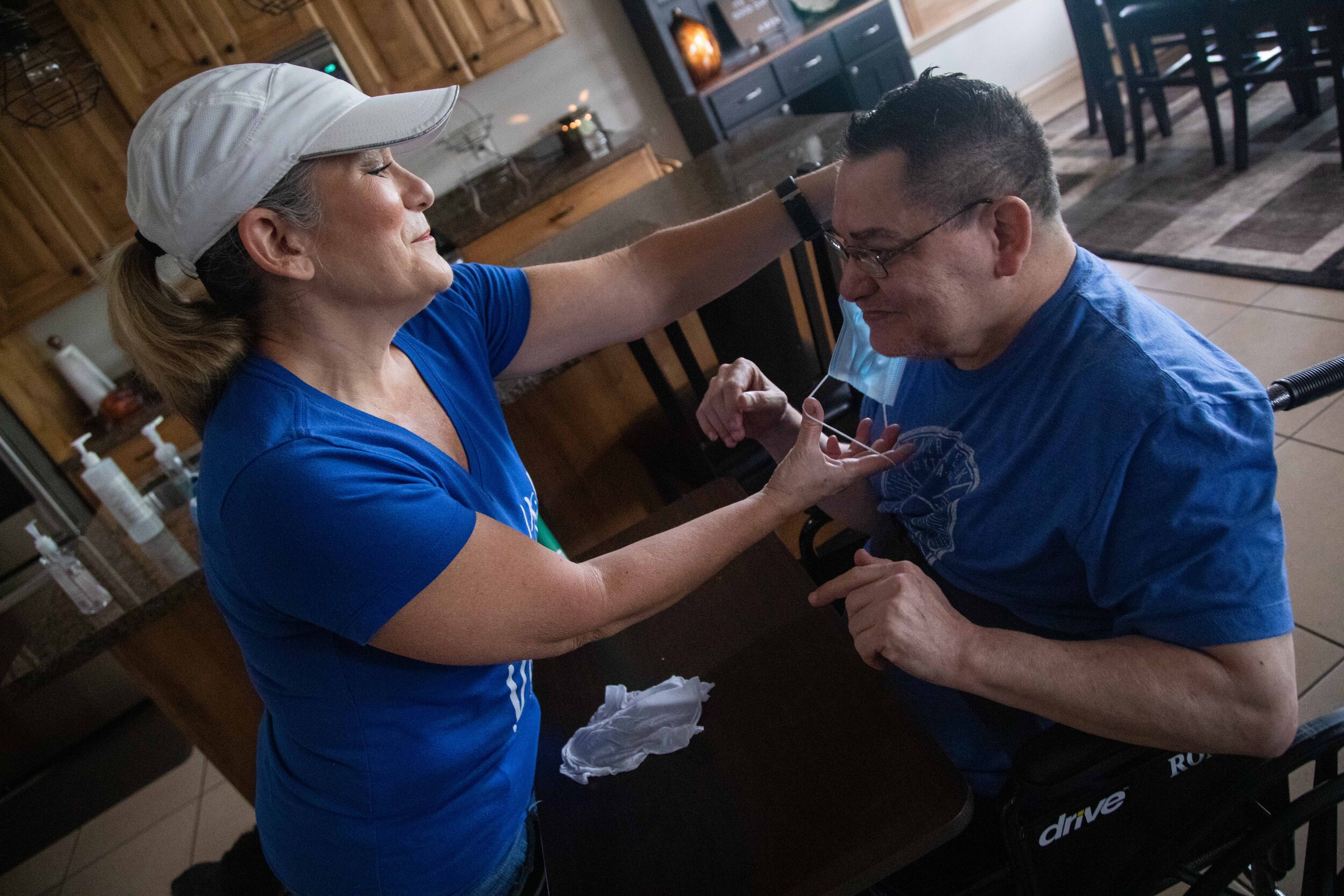  Denise Vigil-Thieldfoldt, left, helps her cousin Ron Vigil put on a mask on Friday, May 22, 2020, in Syracuse, Utah. Ron has Cerebral Palsy. Before living with his cousin, he was a resident at Heritage Park Healthcare and Rehabilitative Services in 