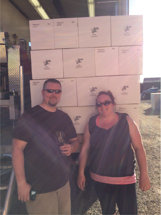 John and Sirpa Peacock standing in front of their first vintage of wine, 2012 Columbia Valley Grenache