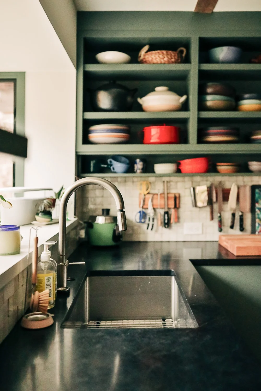 Custom kitchen millwork in mountain home in Bat Cave North Carolina near Lake Lure and Chimney Rock, featuring painted green cabinetry, open shelving, and East Fork Pottery from Asheville NC