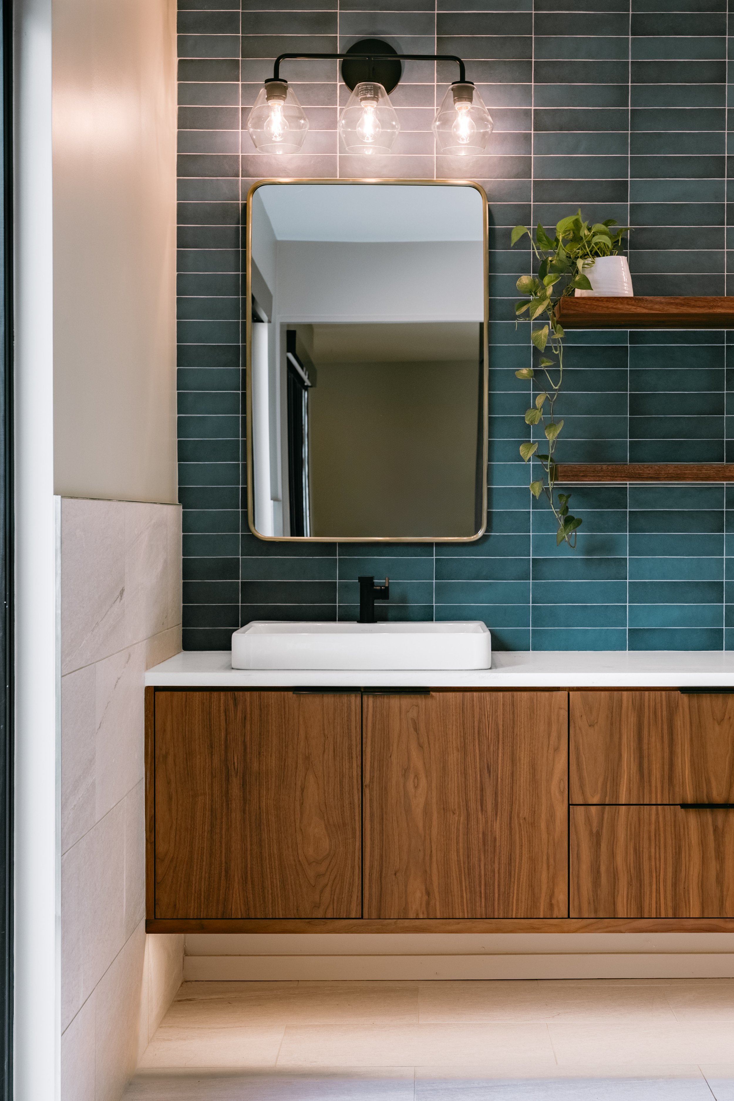 Custom woodwork by Sunnyside Millwork Floating walnut vanity with integrated lighting, quartz countertop, and custom millwork storage in modern bathroom design in Kernersville, North Carolina