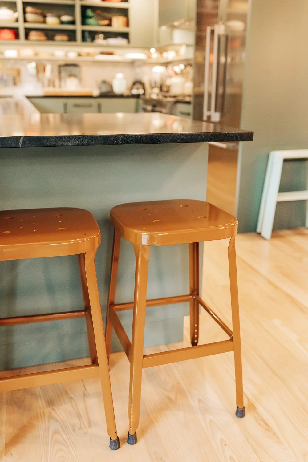 Kitchen seating area with bar stools, painted cabinetry, and integrated storage beneath counter in mountain home