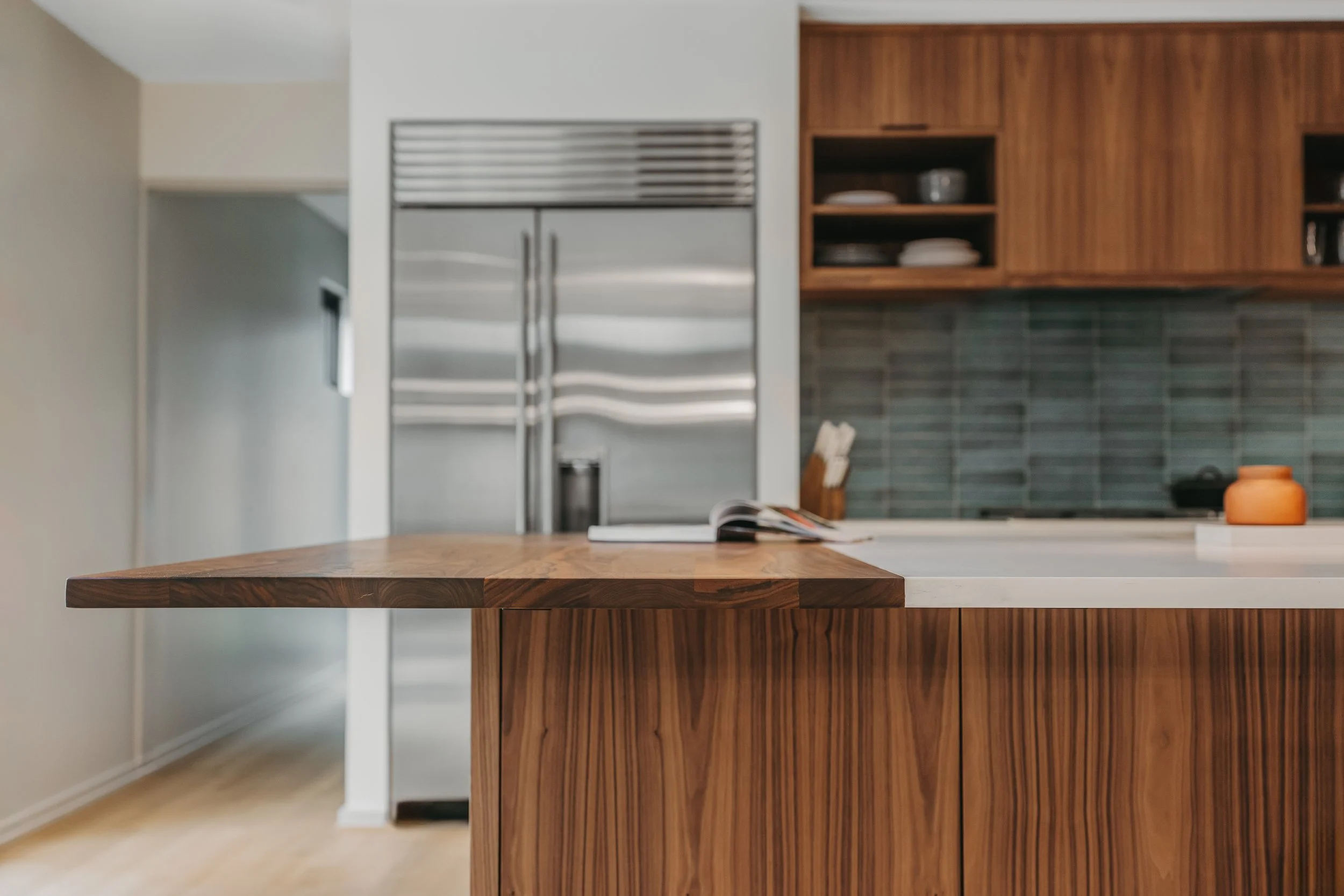 Custom woodwork by Sunnyside Millwork Open concept Two-tone kitchen with grain-matched walnut uppers, white lacquer cabinets, and integrated millwork island with quartz surface in Kernersville, North Carolina