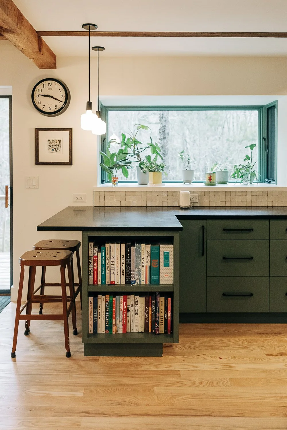 Kitchen seating area with bar stools, painted cabinetry, and Built-in bookshelf integrated into painted kitchen island with custom millwork storage in Bat Cave North Carolina 