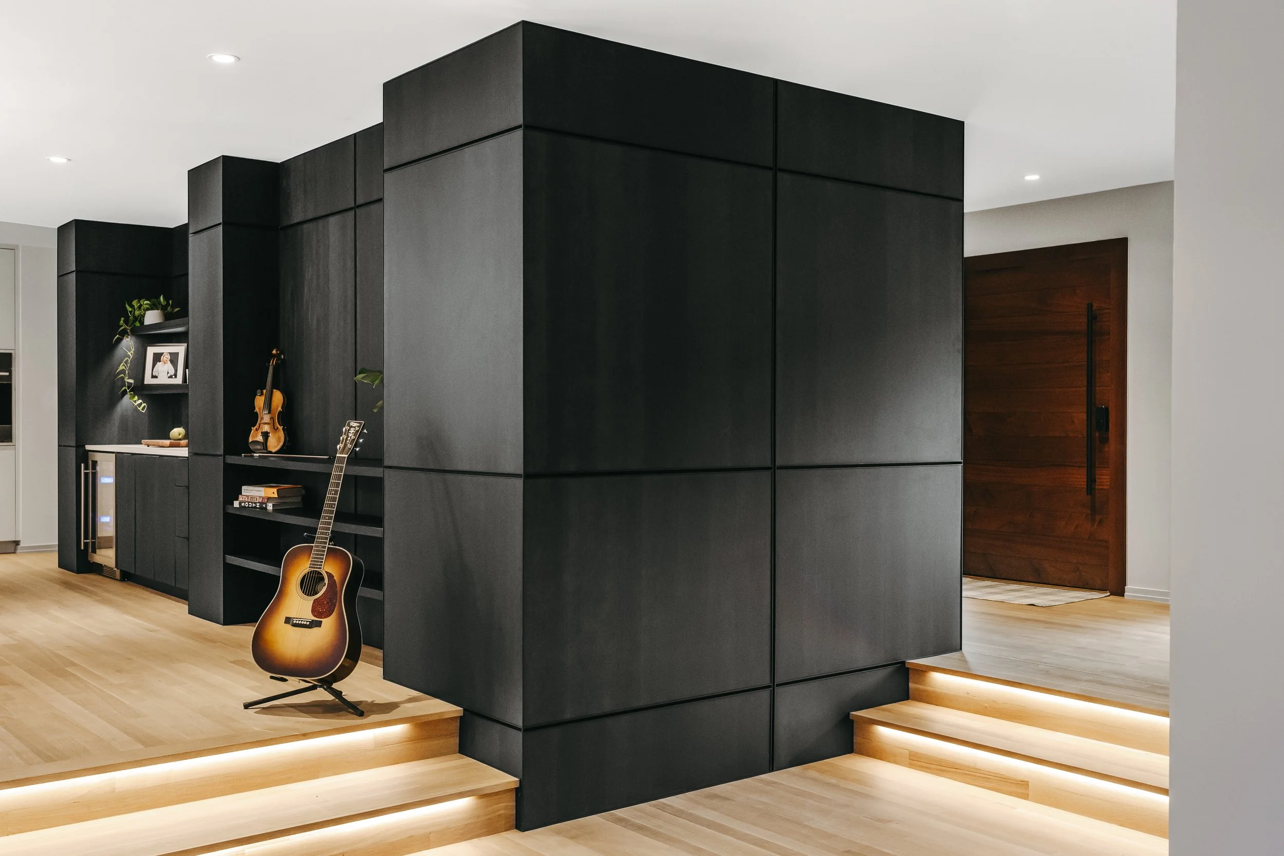 Custom woodwork by Sunnyside Millwork Black rift white oak panel wall with India ink finish and Fry Reglet aluminum reveals creating clean architectural wall transitions in modern kitchen remodel in Kernersville, North Carolina