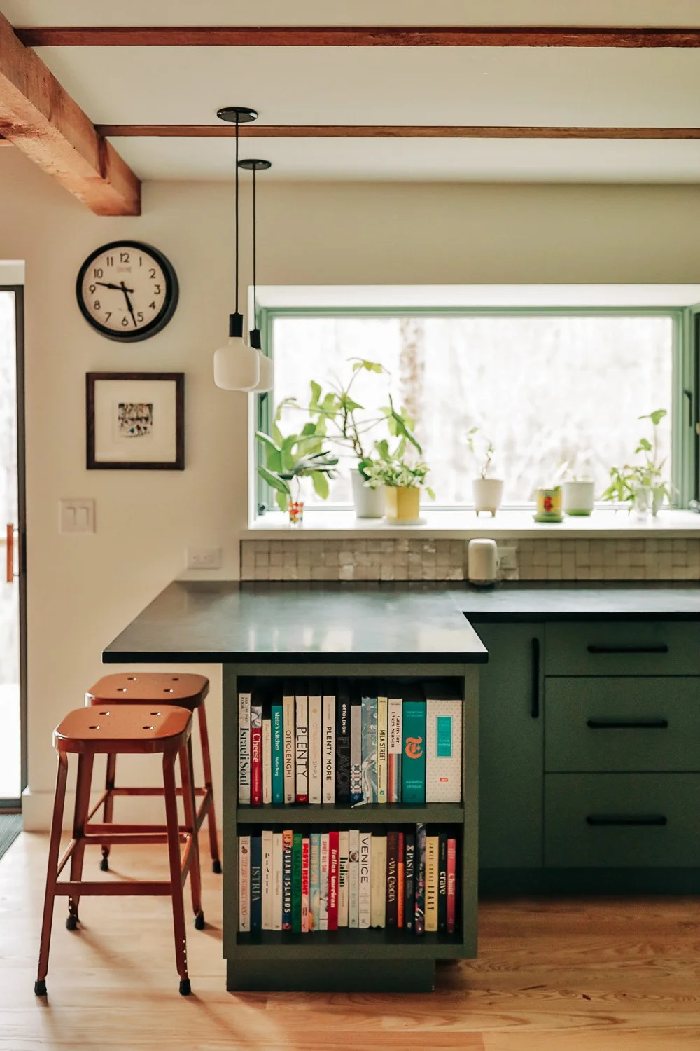 Kitchen seating area with bar stools, painted cabinetry, and Built-in bookshelf integrated into painted kitchen island with custom millwork storage in Bat Cave North Carolina 