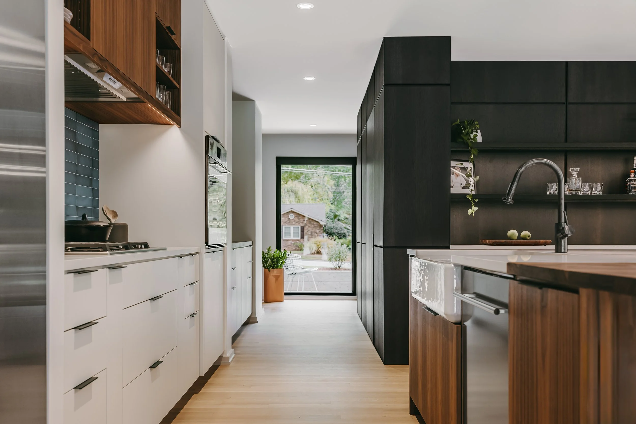 Custom woodwork by Sunnyside Millwork Open concept Two-tone kitchen with grain-matched walnut uppers, white lacquer cabinets, and integrated millwork island with quartz surface in Kernersville, North Carolina