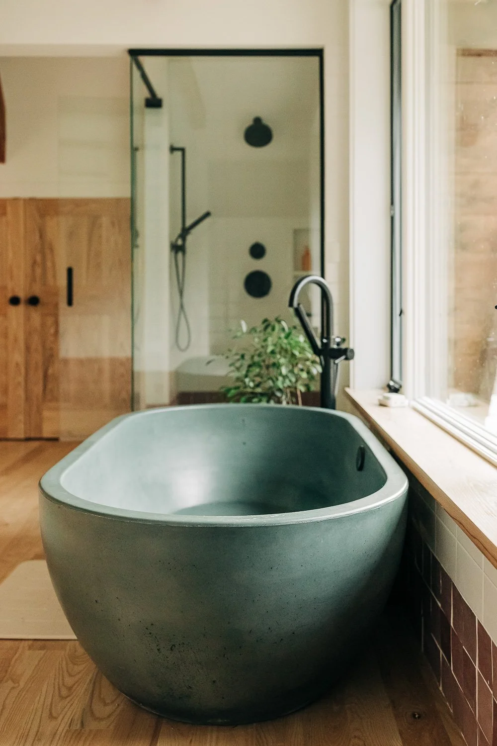 Freestanding concrete soaking tub positioned at window overlooking wooded landscape in Bat Cave NC near Chimney Rock