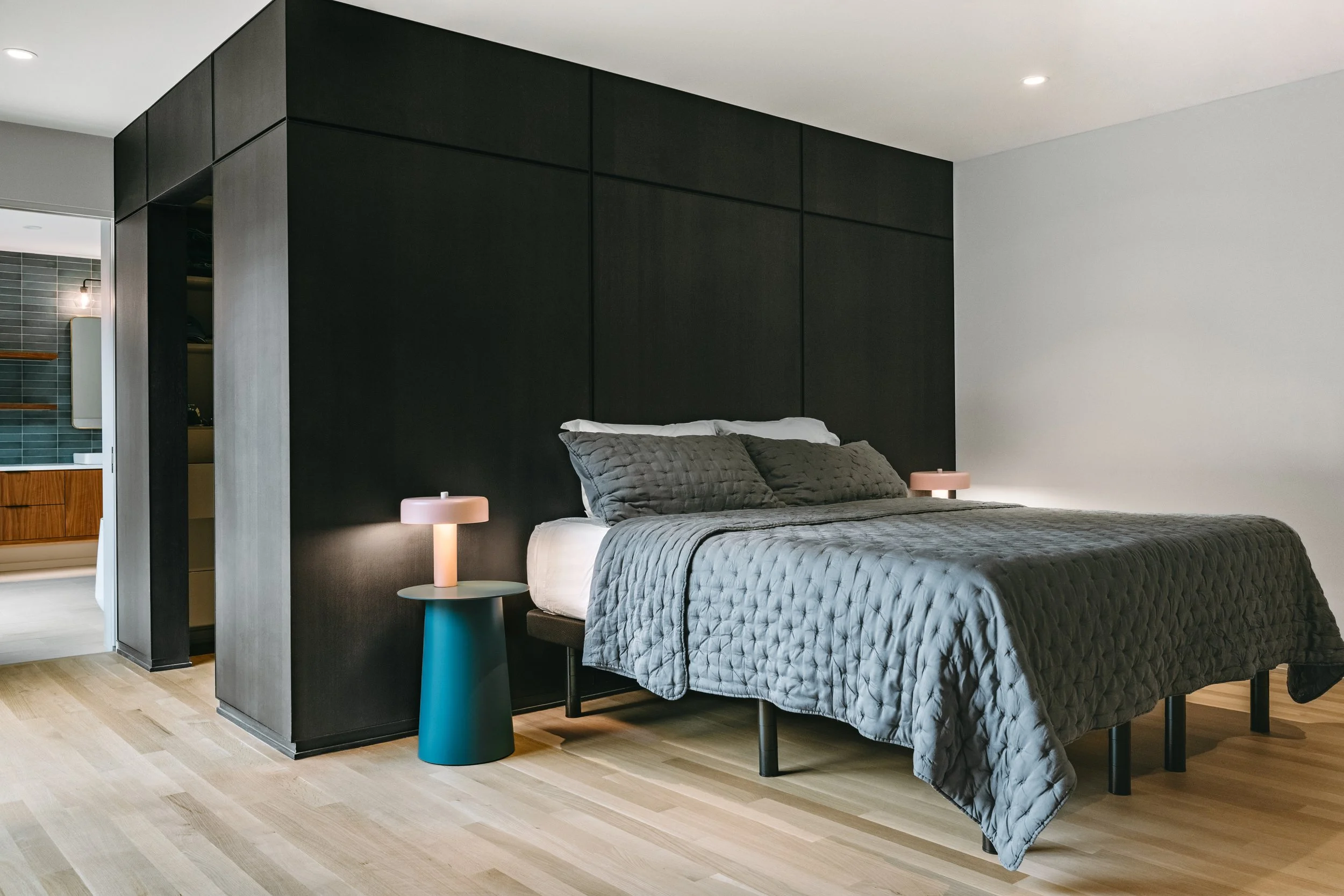 Custom woodwork by Sunnyside Millwork Black rift white oak panel wall with India ink finish and Fry Reglet aluminum reveals creating clean architectural wall transitions in Kernersville, North Carolina integrated flush seams behind bed, custom archit