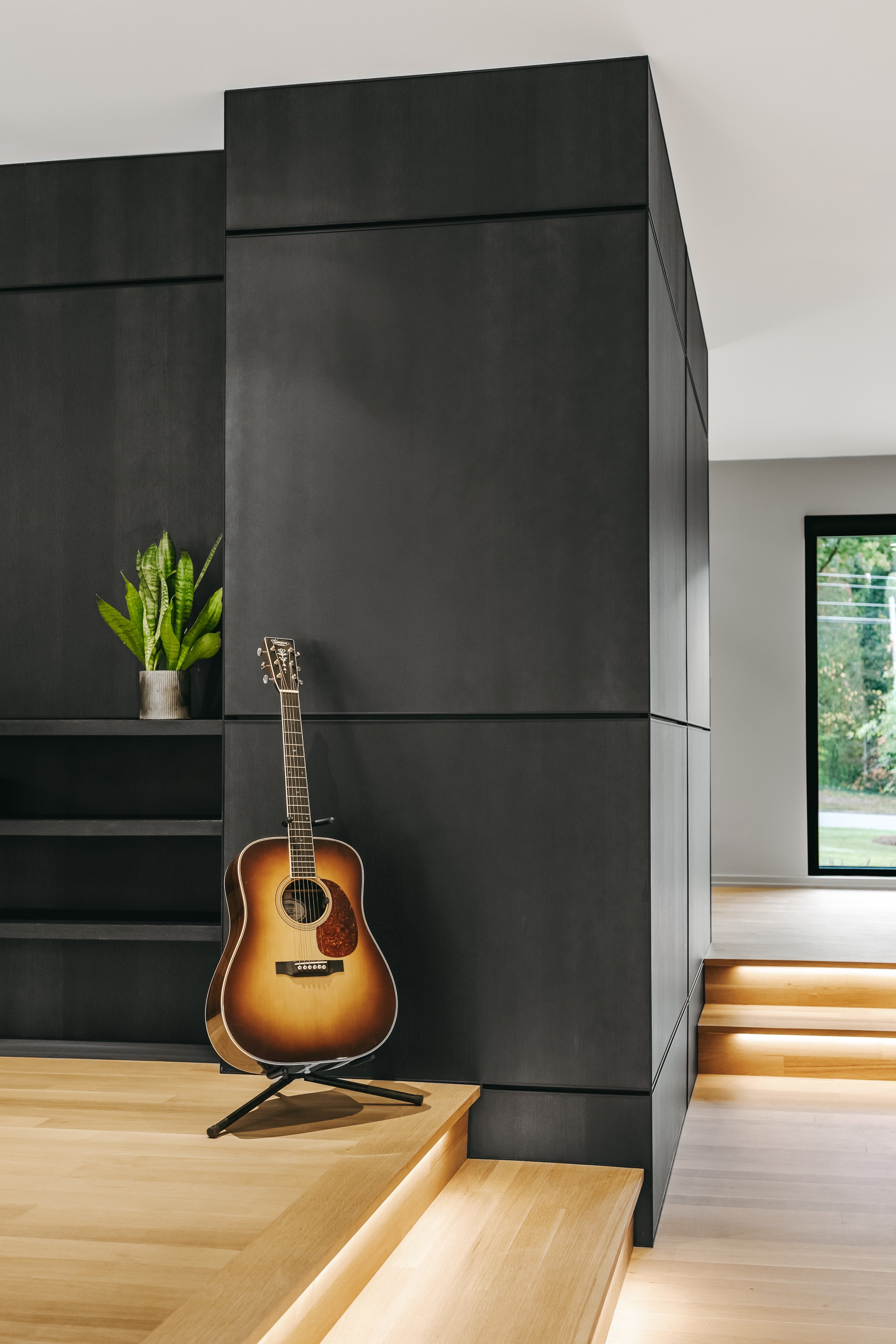 Custom woodwork by Sunnyside Millwork Black rift white oak panel wall with India ink finish and Fry Reglet aluminum reveals creating clean architectural wall transitions in modern kitchen remodel in Kernersville, North Carolina