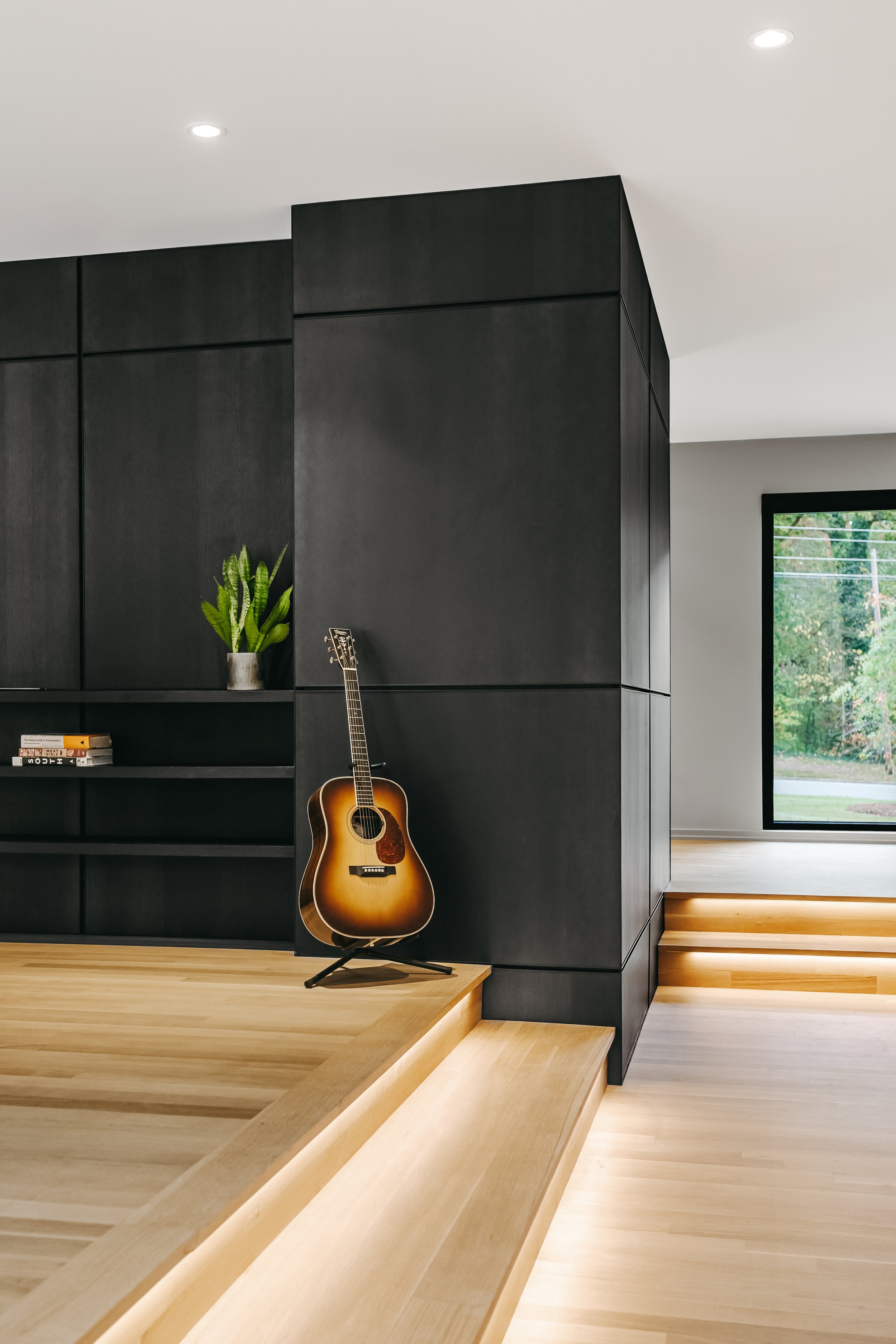 Custom woodwork by Sunnyside Millwork Black rift white oak panel wall with India ink finish and Fry Reglet aluminum reveals creating clean architectural wall transitions in modern kitchen remodel in Kernersville, North Carolina