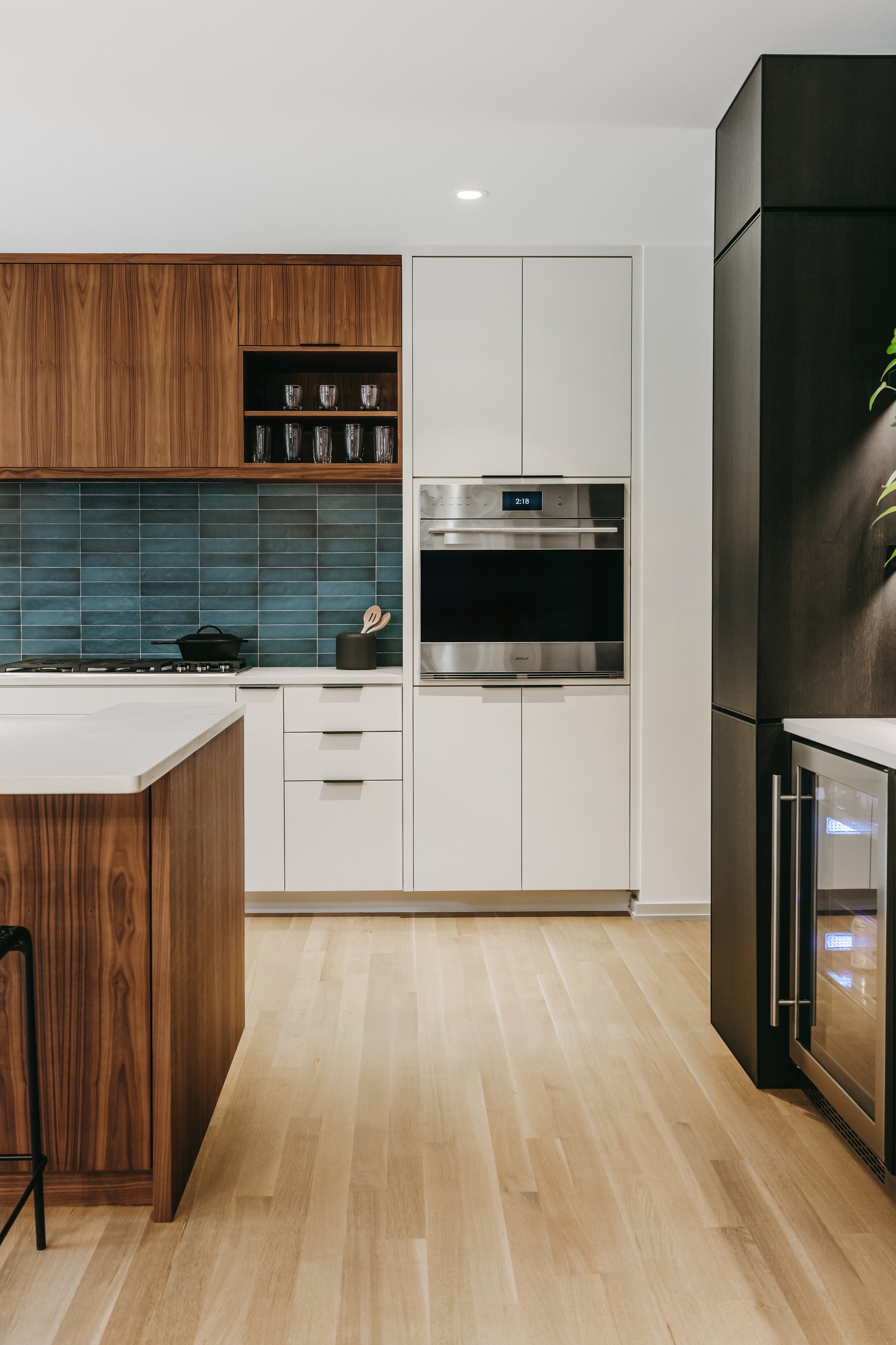 Custom woodwork by Sunnyside Millwork Open concept Two-tone kitchen with grain-matched walnut uppers, white lacquer cabinets, and integrated millwork island with quartz surface in Kernersville, North Carolina