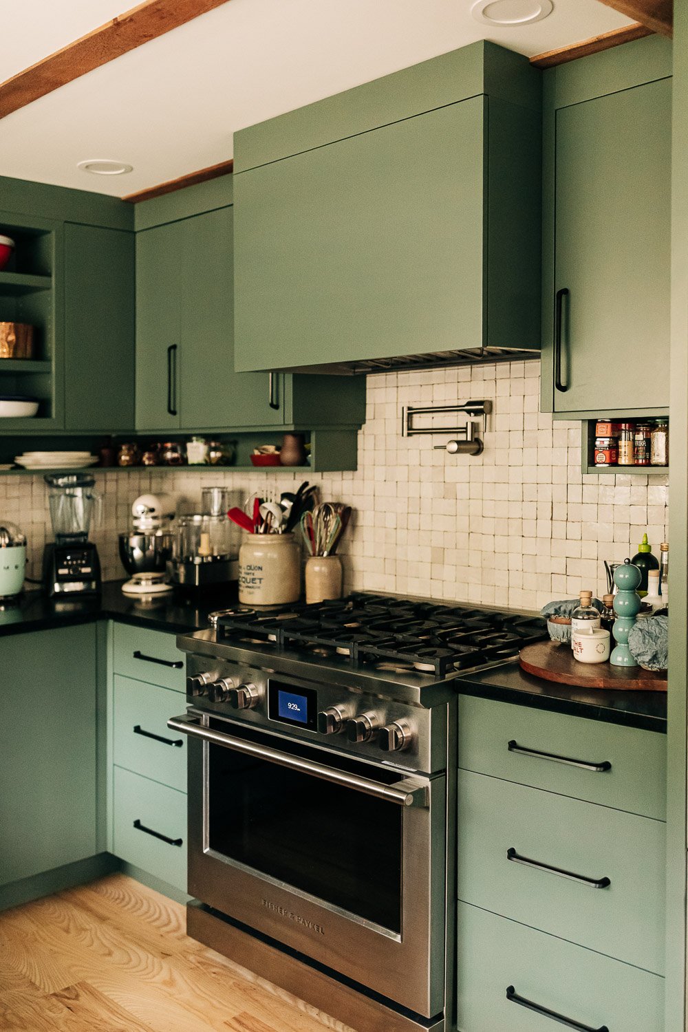 Gas range with integrated pot filler, tile backsplash, and painted cabinetry with custom millwork storage in Bat Cave NC kitchen
