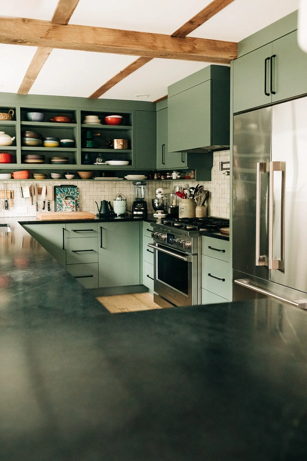 Wide view of kitchen with painted cabinetry, dark countertops, open shelving, and integrated millwork storage in Bat Cave NC
