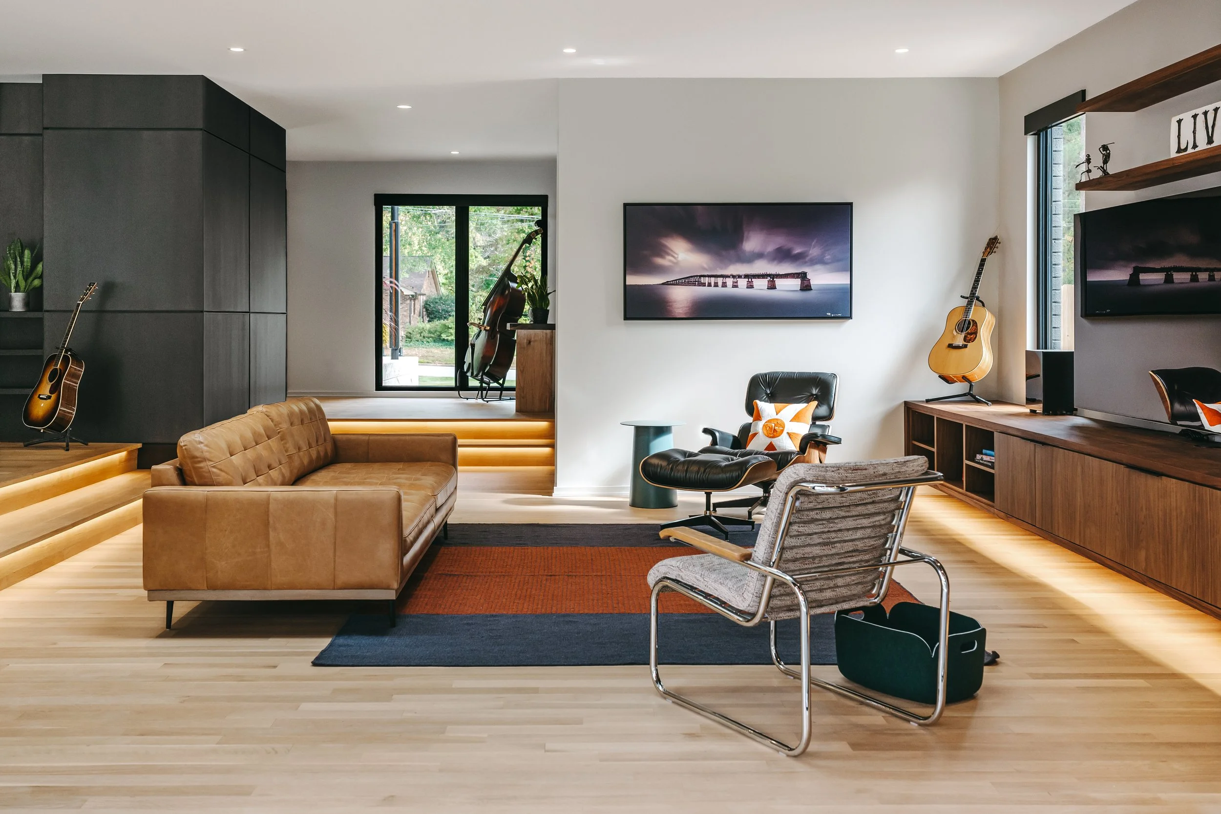 Guitar, modern leather couch, with an Eames black leather chair, Custom woodwork by Sunnyside Millwork Custom 20-foot floating black walnut entertainment center with grain-matched veneer drawer fronts, under lighting, precision scribed to fit irregul