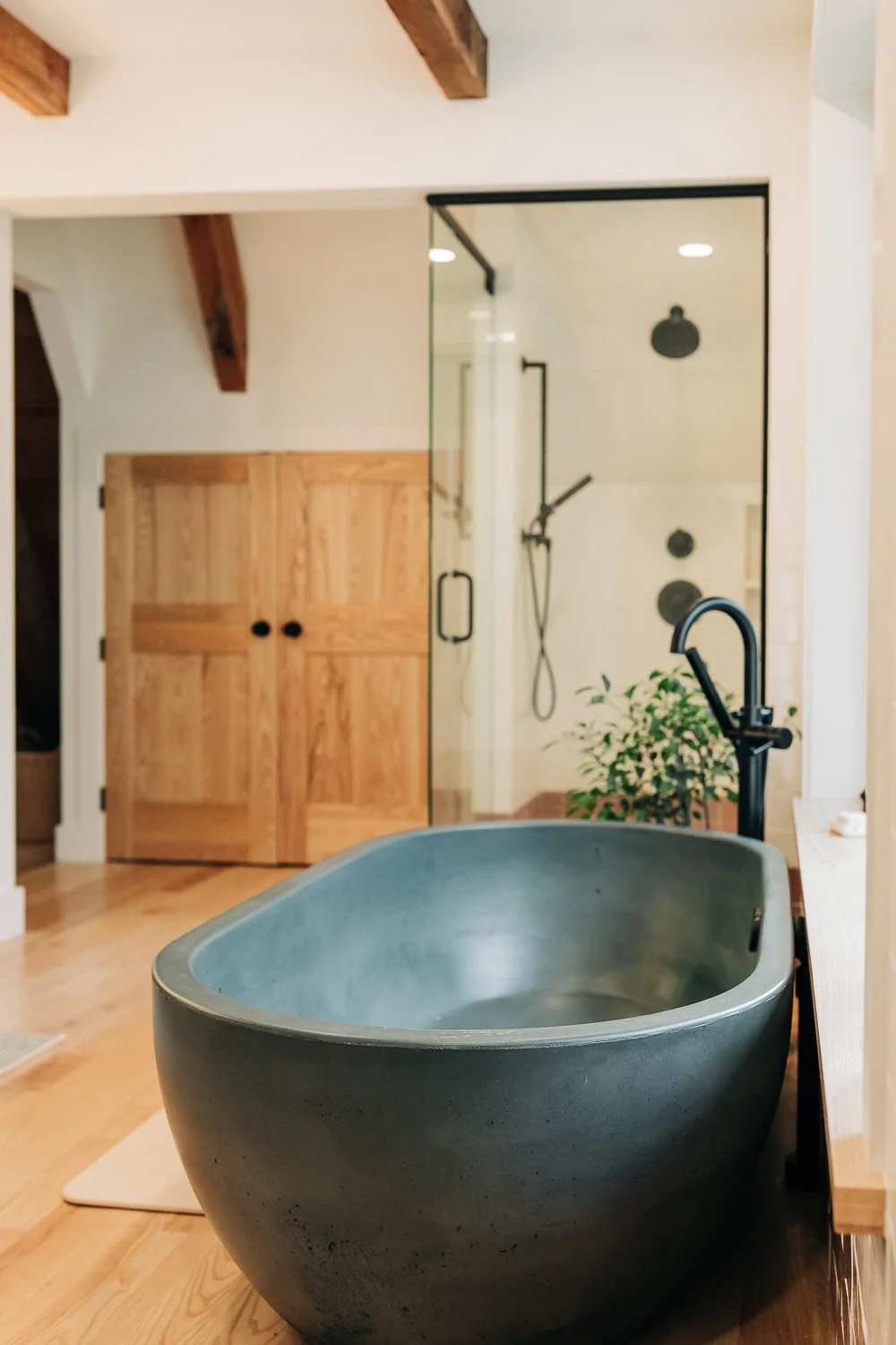 Close-up of freestanding tub with natural light, black fixtures, and surrounding wood finishes and wood built ins in Bat Cave NC