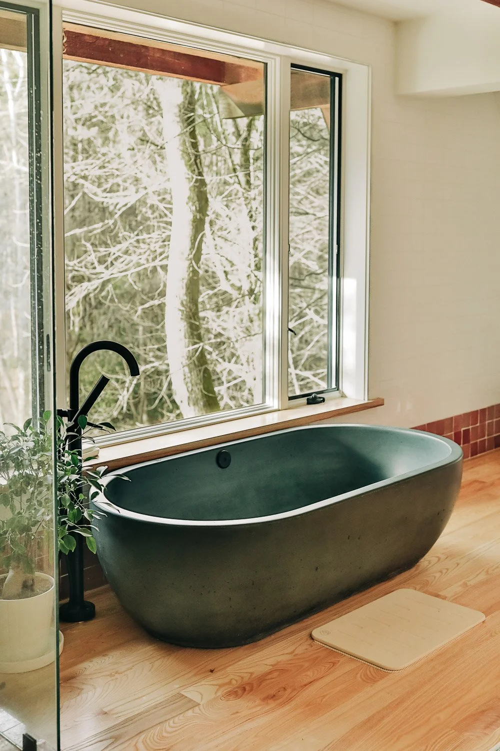 Concrete soaking tub with matte black plumbing fixtures in custom mountain home bathroom near Lake Lure North Carolina