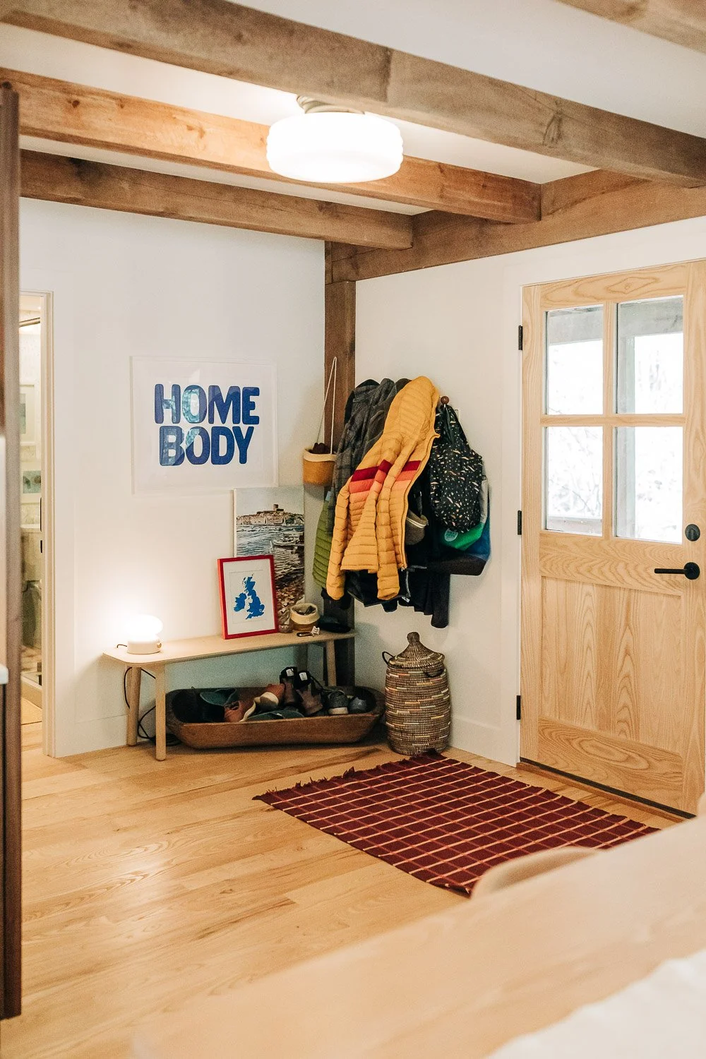 Exterior oak door entryway with coat hooks and bench with exposed wood beams in Bat Cave NC home