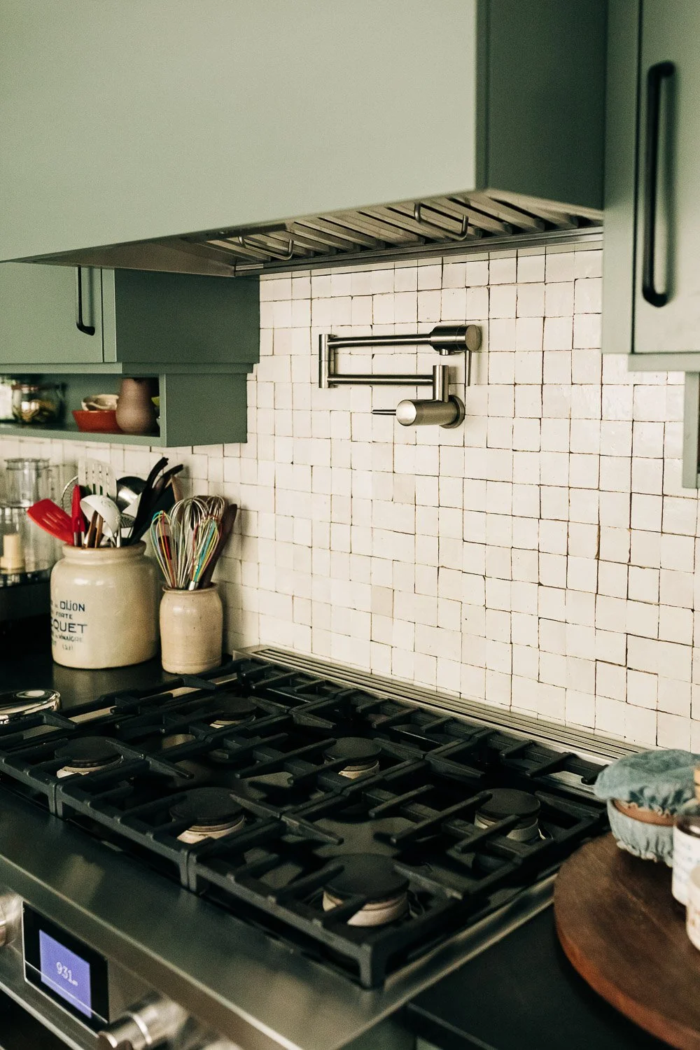 Gas range with integrated pot filler, tile backsplash, and painted cabinetry with custom millwork storage in Bat Cave NC kitchen