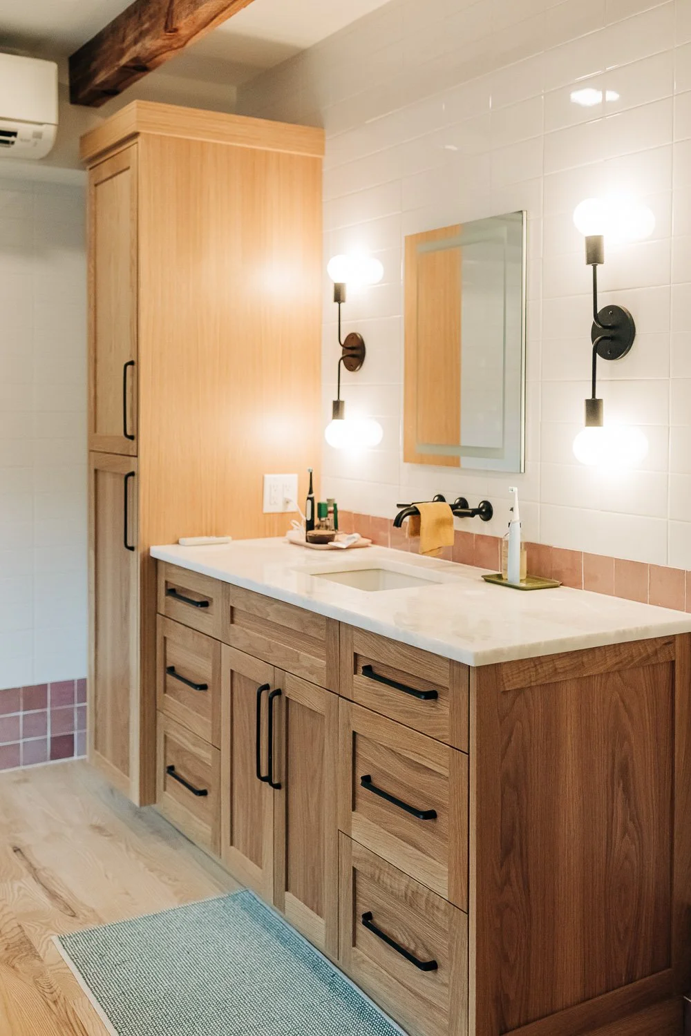Custom white oak vanity with integrated storage, quartz countertop, and wall-mounted fixtures in Bat Cave North Carolina mountain home