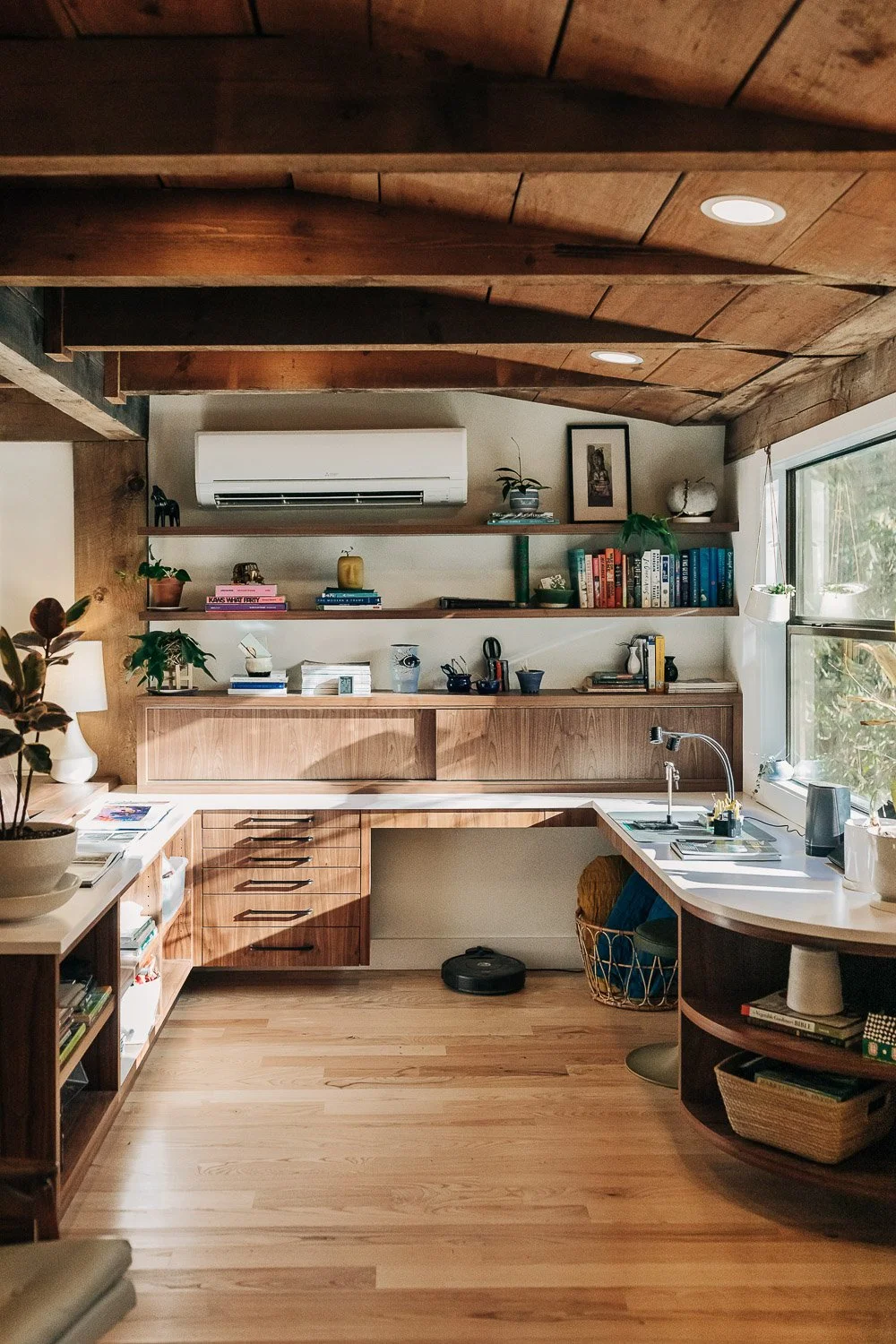 Built-in fly tying station desk with custom black walnut grain matched wood cabinetry and functional storage integrated into millwork system with exposed wood beams, in Bat Cave NC