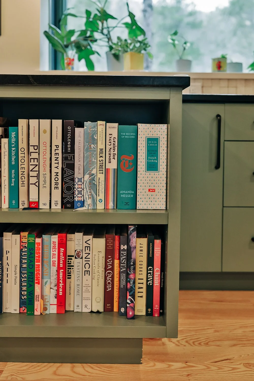 Kitchen seating area with bar stools, painted cabinetry, and Built-in bookshelf integrated into painted kitchen island with custom millwork storage in Bat Cave North Carolina 