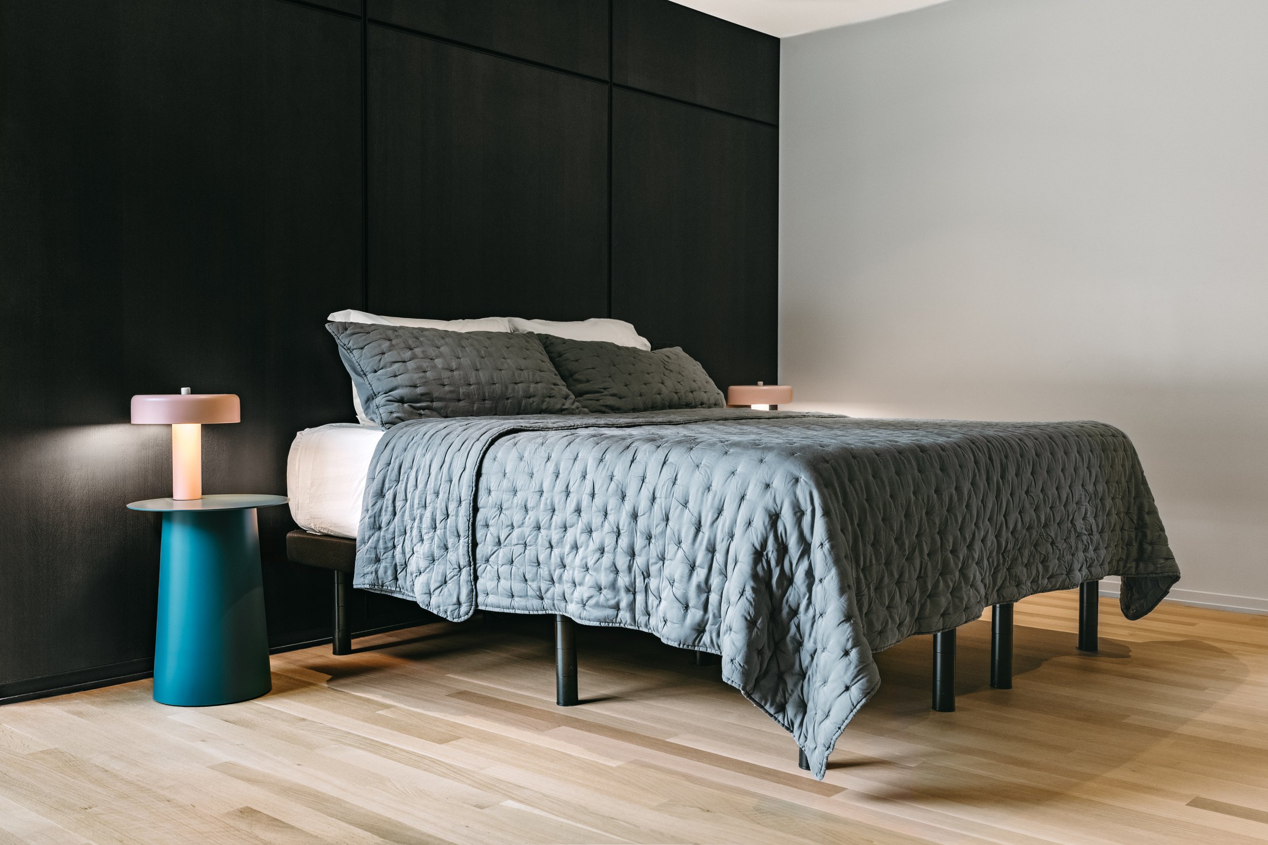 Custom woodwork by Sunnyside Millwork Black rift white oak panel wall with India ink finish and Fry Reglet aluminum reveals creating clean architectural wall transitions in Kernersville, North Carolina integrated flush seams behind bed, custom archit