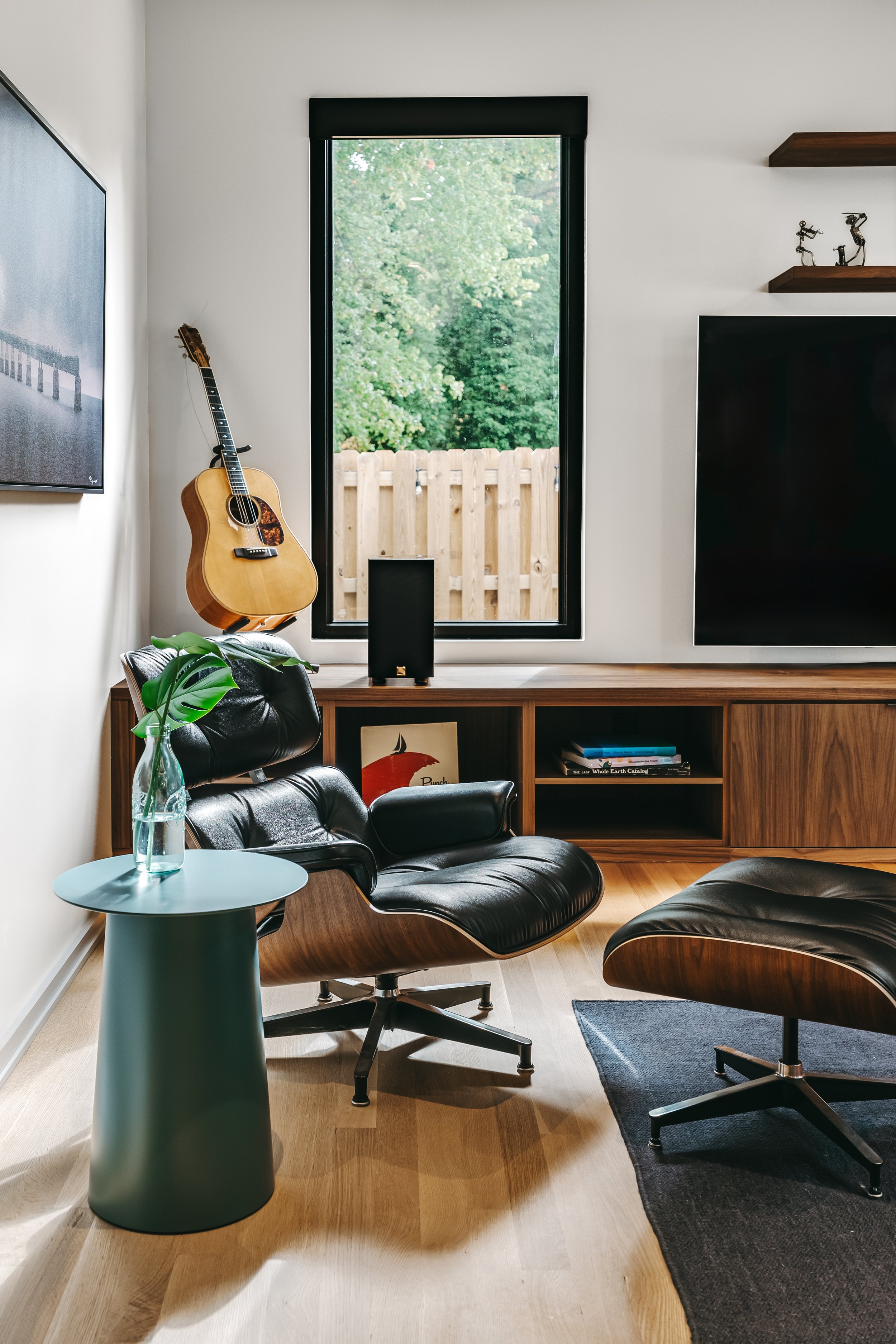 Guitar, modern leather couch, with an Eames black leather chair, Custom woodwork by Sunnyside Millwork Custom 20-foot floating black walnut entertainment center with grain-matched veneer drawer fronts, under lighting, precision scribed to fit irregul